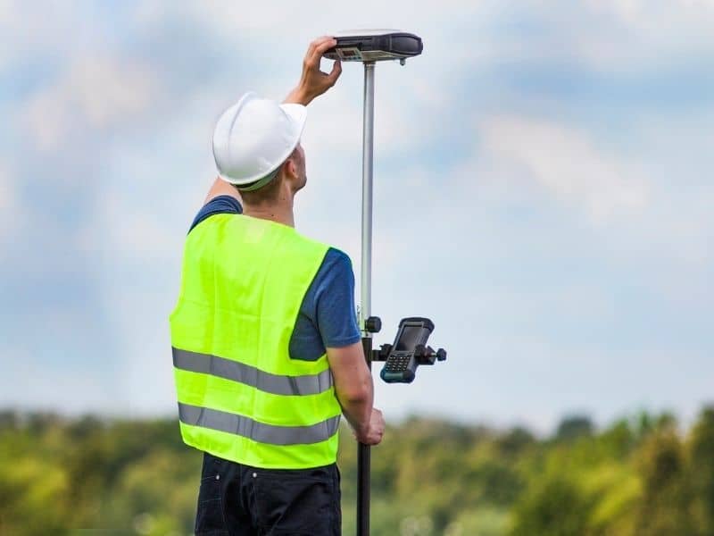 Construction surveyor using GPS equipment to support warehouse truck court and loading area expansion planning.